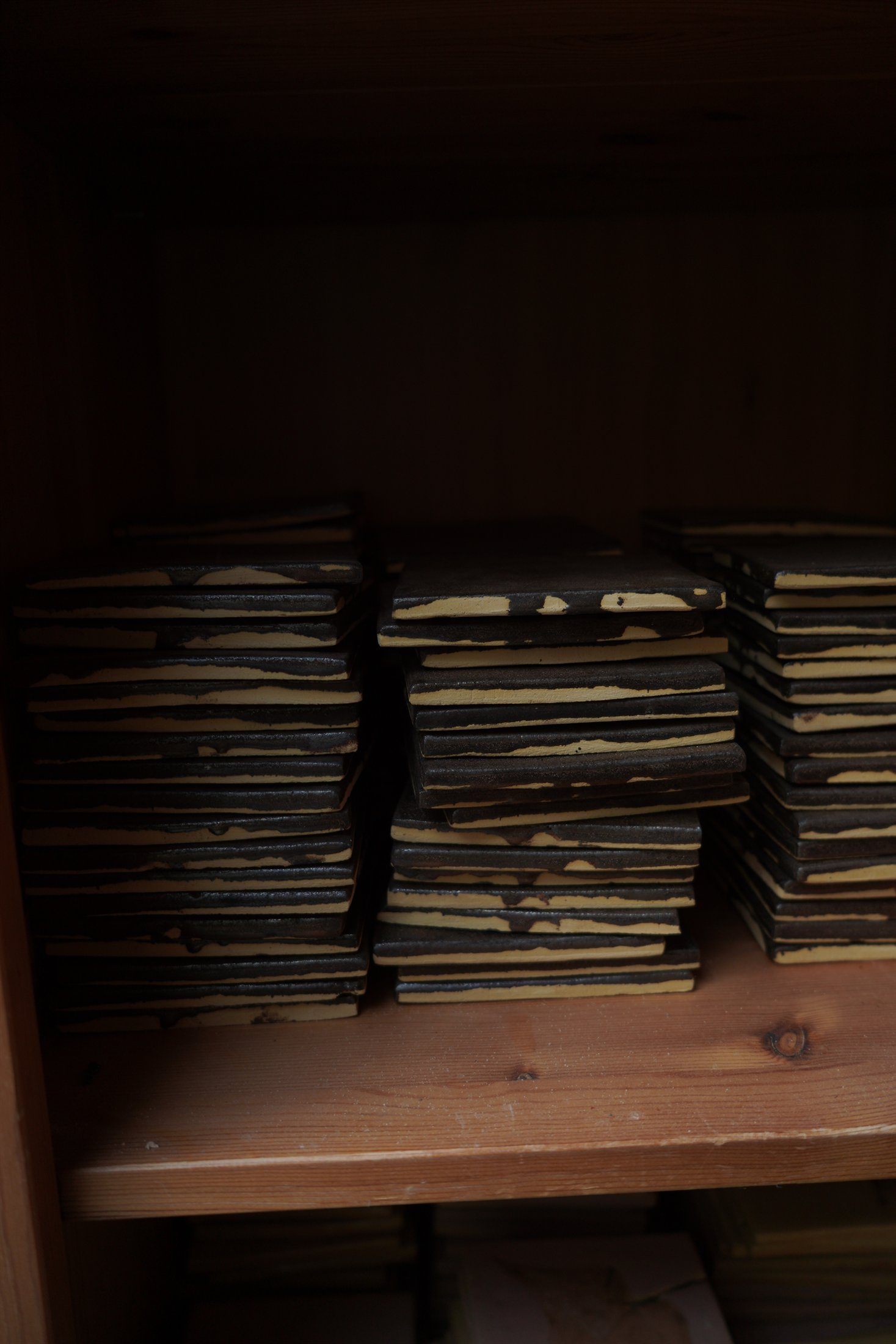 Finished handmade tile stacks held on atelier shelving.