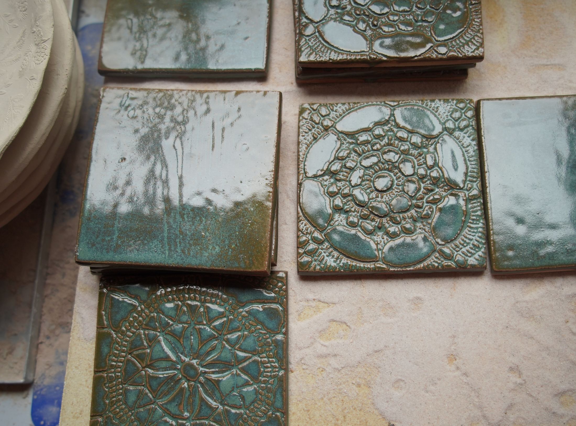 Handgemaakte Verdigris-tegels met mineraalgroen glazuur en reliëfvariatie.